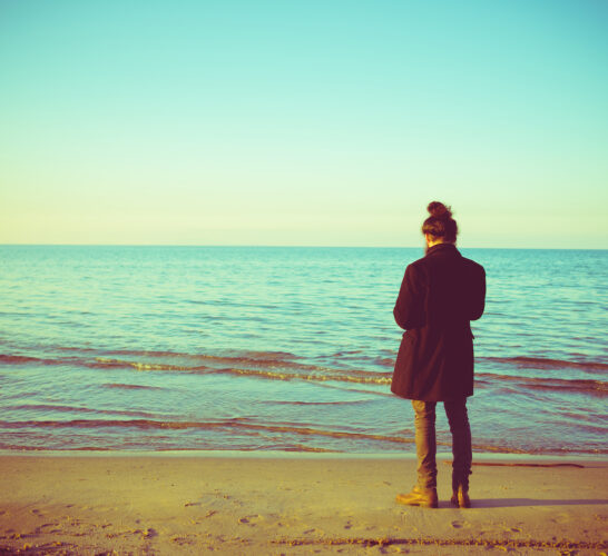 Back view of a man standing at the shoreline and looking in the winter.