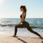 Health conscious woman on a beach doing lunges exercises