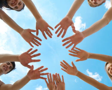 Circle of people's hands on a blue sky background