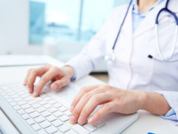 Close-up of a medical worker typing on a computer.