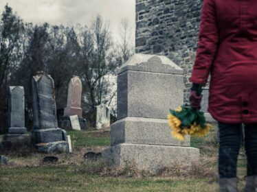 Woman standing at a grave in a cemetary