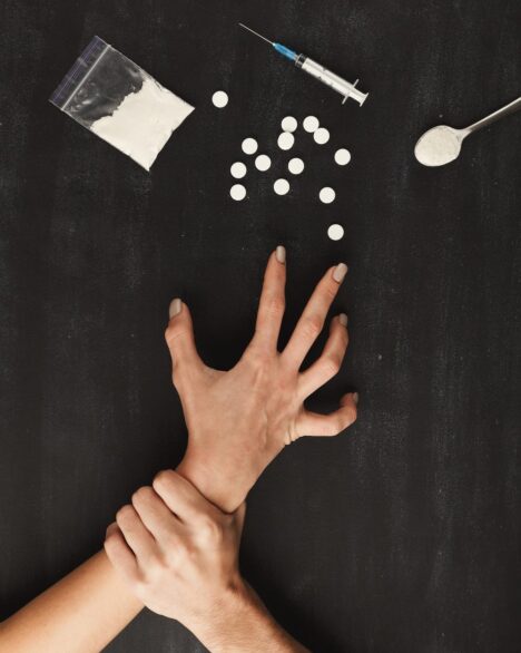 Addict's hands on table with drugs