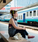 Woman sitting on a bench waiting at the train station.
