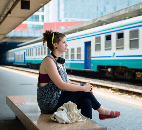 Woman sitting on a bench waiting at the train station.