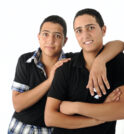 Two young male friends leaning against a wall supporting one another.