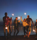 Young friends enjoying a beach party with sparklers in the early evening.